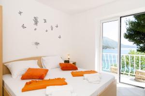 a white bed with orange pillows in a room with a window at Guest House Daniela in Mlini