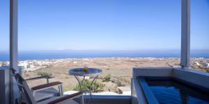 a balcony with a swimming pool and a table and chairs at Muses Cycladic Suites in Oia
