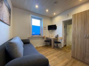 ein Wohnzimmer mit einem blauen Sofa und einem Schreibtisch in der Unterkunft Pensionszimmer Hannes in Lübeck