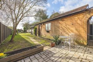 a patio with a table and chairs next to a brick building at COSY HOME NEAR DORNEY, WINDSOR & Free Parking in Taplow