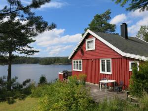 a red house with a deck next to a lake at Holiday Home Ogge - SOO690 by Interhome in Svaland