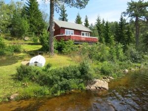 a red house with a white tent next to a river at Holiday Home Ogge by Interhome in Svaland