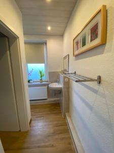 een badkamer met een wastafel, een toilet en een raam bij Pensionszimmer Hannes in Lübeck