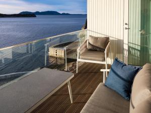 einen Balkon mit einem Sofa und einem Stuhl auf dem Wasser in der Unterkunft Holiday Home Svortevik - FJS077 by Interhome in Førde