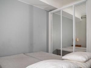 a white bedroom with two beds and a mirror at Holiday Home Villa ylläs 201 by Interhome in Ylläs