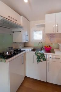 a white kitchen with white cabinets and a sink at Holiday Home Ostro by Interhome in Marina di Bibbona +17 photos