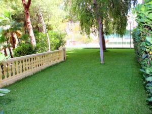 a garden with a wooden fence and green grass at Apartment Cardenal II by Interhome in Cala de Finestrat