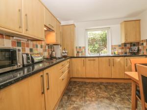 a large kitchen with wooden cabinets and a window at Little Acre in Torquay