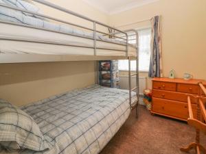a bedroom with two bunk beds and a dresser at Little Acre in Torquay