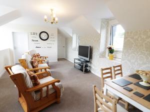 a living room with a table and chairs and a tv at Station Apartment in Llanberis