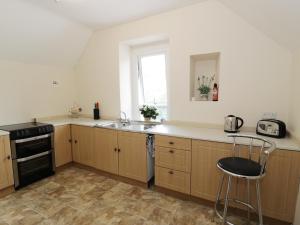 cocina con armarios de madera, fregadero y ventana en Station Apartment, en Llanberis