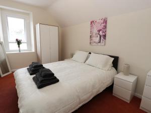 Un dormitorio con una cama blanca con toallas negras. en Station Apartment, en Llanberis