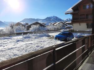 une voiture bleue garée dans une cour recouverte de neige dans l'établissement Apartment Mösli - Zimmerli by Interhome, à Zweisimmen