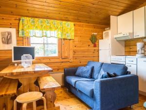 a living room with a blue couch and a table at Holiday Home Niemenkärki by Interhome in Kortteinen