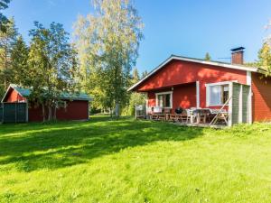 a red house on a grassy field next to a house at Holiday Home Saniainen 5 by Interhome in Säviä