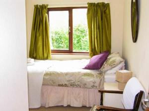 a bedroom with a bed with green curtains and a window at Bryn yr Haf in Llanfair Clydogau