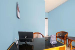 Zimmer mit einem Schreibtisch, einem TV und Stühlen in der Unterkunft RedDoorz Syariah At Jl Pangeran Hidayatullah Cianjur in Cianjur + 21 Fotos