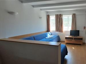 uma sala de estar com um sofá azul e uma televisão em Apartment Estudio by Interhome em Sintra