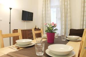 a dining room table with plates and glasses and a vase with flowers at Modern Apartment Ve Smečkách 28 in Prague