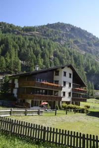 a large building with a fence in front of a mountain at Apartment Sunshine by Interhome in Saas-Grund