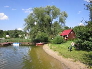 RaszągにあるDom nad Jezioremの赤納屋と家の川