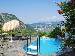 a swimming pool with chairs and an umbrella at Holiday Home Ursula by Interhome in Pugerna