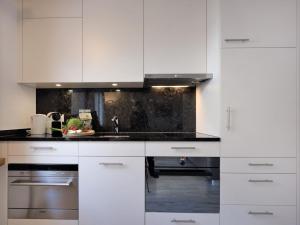a kitchen with white cabinets and a sink at Apartment Chesa Munteratsch 311 by Interhome in Silvaplana