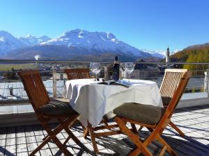 a table with wine glasses on a balcony with a mountain at Apartment Chesa Crusch 7 by Interhome in Samedan