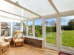 a conservatory with windows and a couch and chair at Skylark in Holt