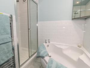 a white bathroom with a tub and a glass shower at The Tynemouth Cottage in Tynemouth +7 photos