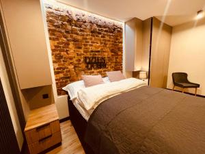 - une chambre avec un lit et un mur en briques dans l'établissement Apartamenty KTW Park Śląski - Family DELUX, à Katowice