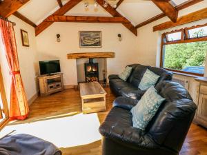 a living room with a leather couch and a fireplace at Stable Cottage in Clynderwen