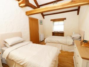a bedroom with two beds and a window at Stable Cottage in Clynderwen