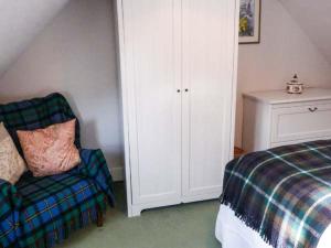 a bedroom with a bed and a chair and a cabinet at Riemore in Tomintoul