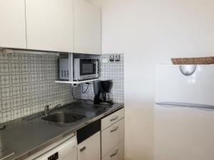 a white kitchen with a sink and a microwave at Apartment Les Cascadelles-2 by Interhome in La Foux +14 photos
