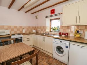 a kitchen with a washing machine and a table at Chestnut Cottage in Great Edston