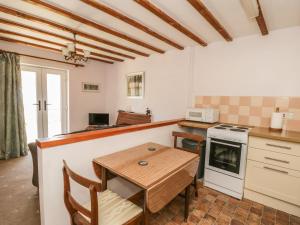 a kitchen with a table and a stove and a microwave at Chestnut Cottage in Great Edston