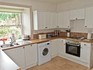 a kitchen with white cabinets and a sink and a dishwasher at Alpine Cottages No 4 in Reeth