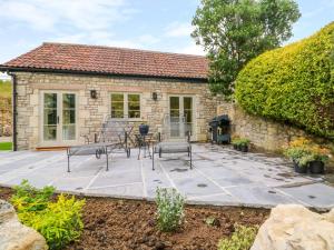 a stone house with a patio and a fireplace at Pheasant Cottage in Bath