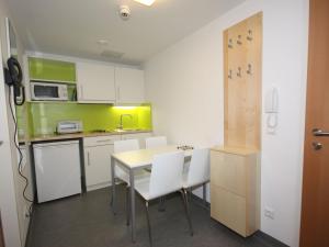 a small kitchen with a table and white chairs at Apartment smart living by Interhome in Sankt Ulrich