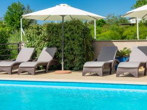 grupa krzeseł i parasol obok basenu w obiekcie Apartment Villa Jadranka-2 by Interhome w mieście Štinjan