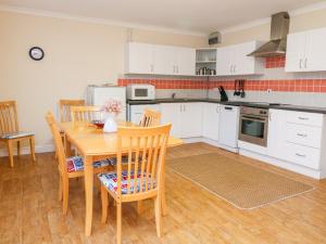 a kitchen with white cabinets and a wooden table and chairs at Tynk in Saint Merryn