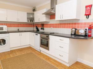 a kitchen with white cabinets and a black counter top at Tynk in Saint Merryn