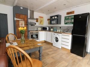 eine Küche mit einem Tisch und einem schwarzen Kühlschrank in der Unterkunft Foxley Wood Cottage in Horsham St Faith