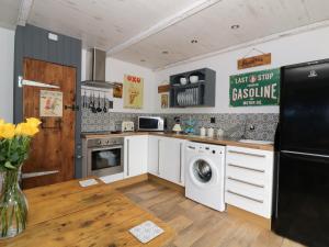 cocina con nevera negra y mesa en Foxley Wood Cottage, en Horsham St Faith