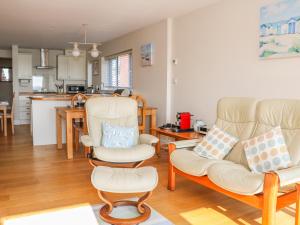 a living room with two chairs and a kitchen at Harbour View, Mudeford in Christchurch