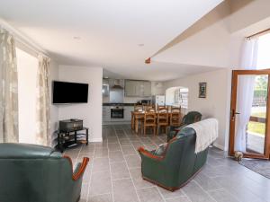 a living room with green chairs and a kitchen at Cilgwyn Bach in Llandysul