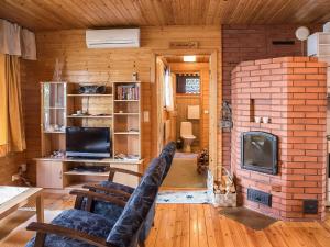 a living room with a brick fireplace and a tv at Holiday Home Kettukallio by Interhome in Luhtanen