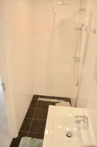 a white bathroom with a shower and a sink at De Wulk 26 in Zandvoort