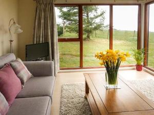 a living room with a couch and a table with yellow flowers at Pine Lodge in Resolis